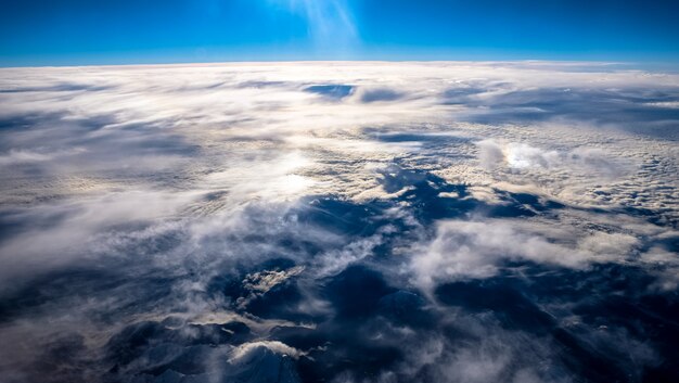 Beautiful view of the clouds and mountain under a clear sky shot from an airplane