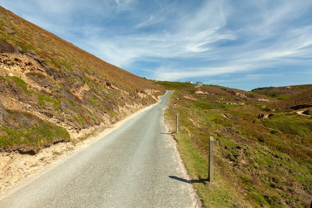 Beautiful view of the country road in Cornwall, the UK under the blue sky