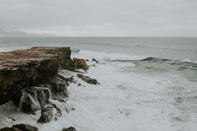 Beautiful view of foamy waves reaching rocky shore