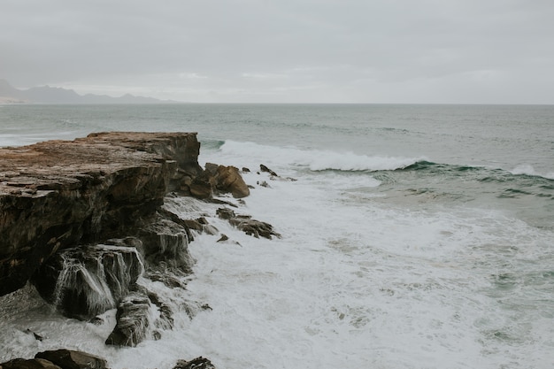 岩の多い海岸に到達する泡の波の美しい景色