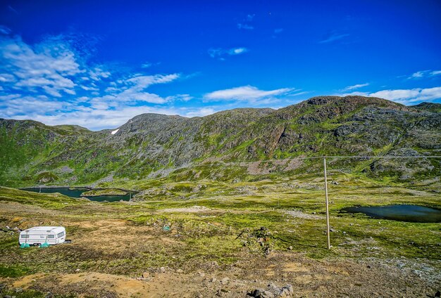 Beautiful view of the grass-covered mountains and fields under the clear blue sky in Sweden