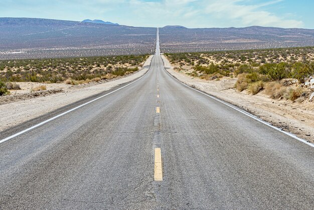 砂漠地帯の間の長くまっすぐなコンクリート道路の美しい景色