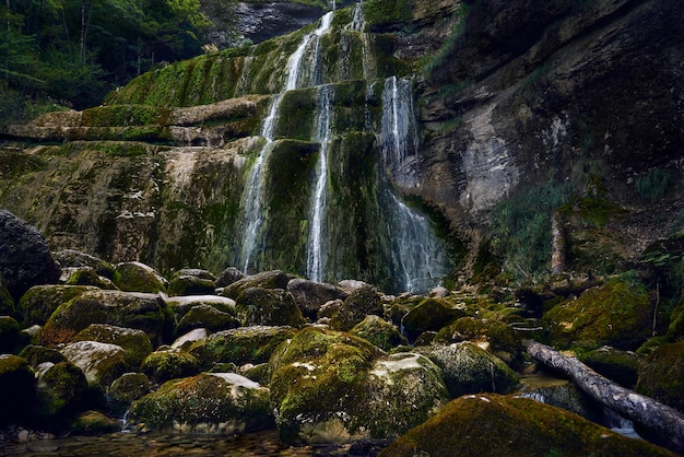 苔に覆われた岩と崖の上の滝の美しい景色