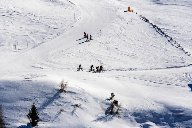 Beautiful view of people cycling and skiing across snowy mountains in South Tyrol, Dolomites, Italy