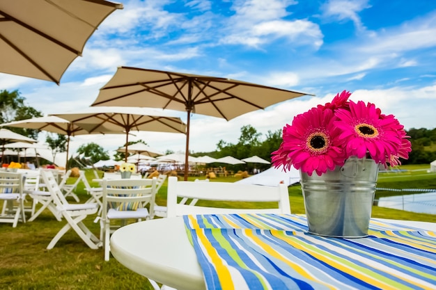 Beautiful view of pink flowers in a basket on the table with umbrellas in the wall