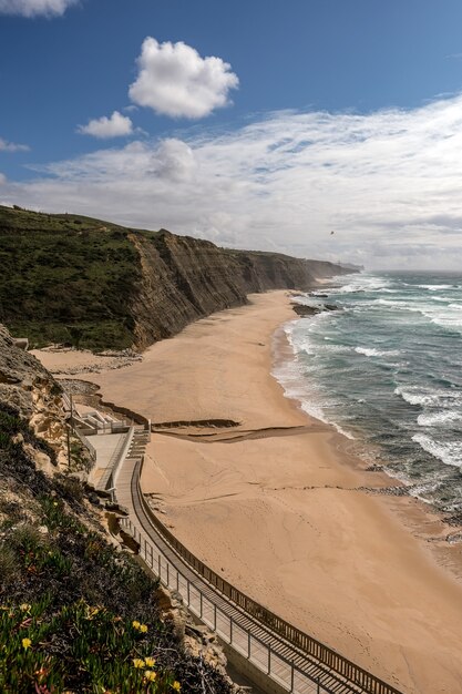 Beautiful view of sandy beach with a pathway on the cliff