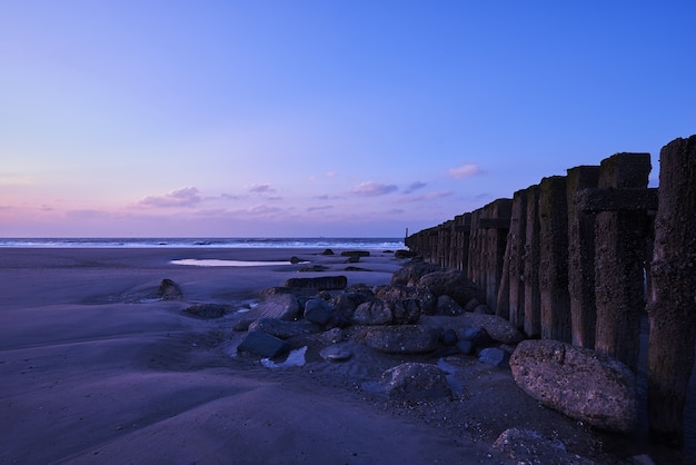 Beautiful view of the sunset with purple clouds over the fence on the beach