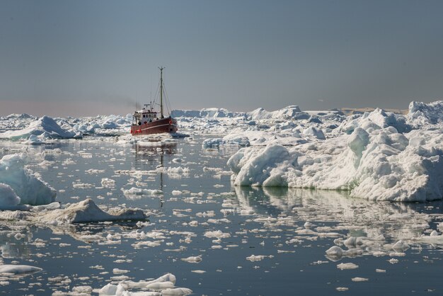 Прекрасный вид на туристическую лодку, плывущую через айсберги в заливе Диско, Гренландия