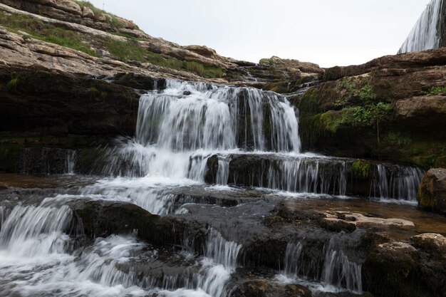 Beautiful view of the waterfall streaming down the cliffs covered in moss