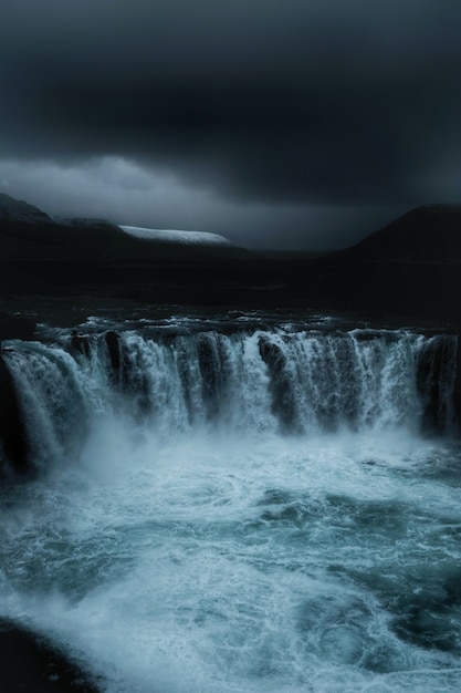 A beautiful waterfall in a field with dark sky