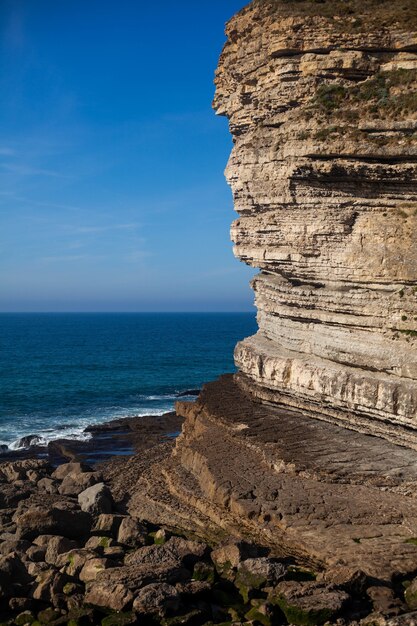 Beautiful wavy ocean hitting the rocky cliffs under the cloudy sky