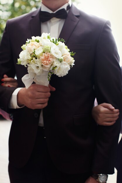 Beautiful wedding bouquet in hands of the groom.