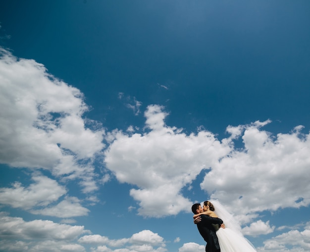 青い空を背景に美しい結婚式のカップル