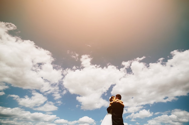 青い空を背景に美しい結婚式のカップル