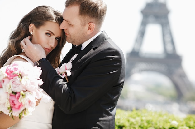 Beautiful wedding couple has fun posing on the square before the Eiffel Tower in Paris