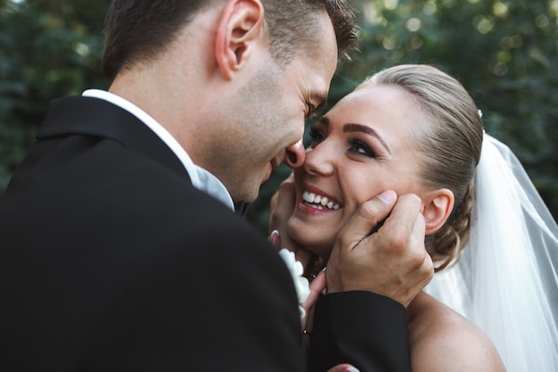 公園でポーズをとって美しい結婚式のカップル