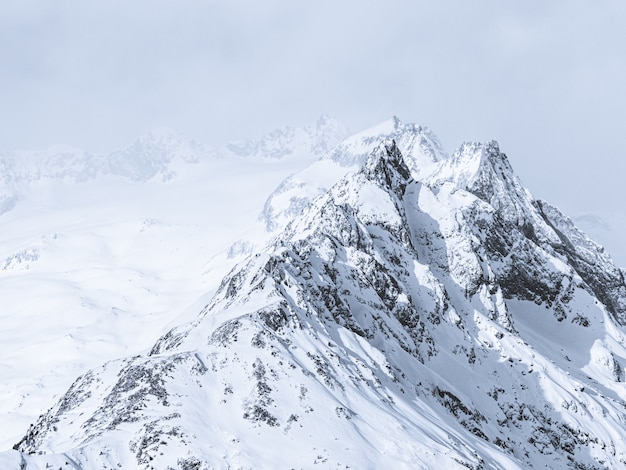 Beautiful wide shot of mountains covered in snow under a foggy sky