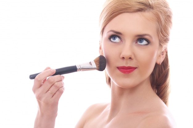 Beautiful woman applying make up with brush