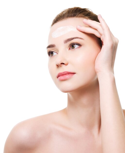 Beautiful woman applying moisturizer cosmetics on forehead