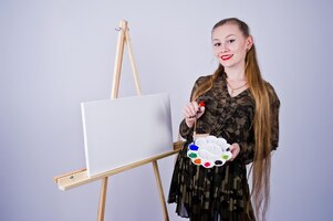 Bella donna artista pittore con spazzole e tela a olio in posa in studio isolato su bianco