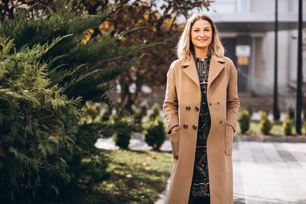 Beautiful woman in a beige coat outside in park