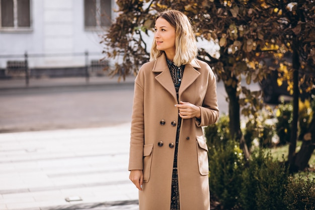 Bella donna in un cappotto beige fuori nel parco