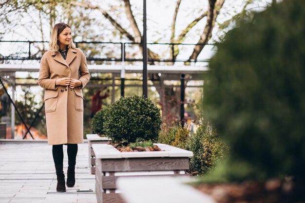 Beautiful woman in a beige coat outside in park