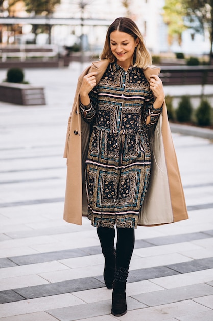 Free photo beautiful woman in a beige coat outside in park