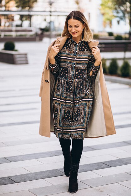 Beautiful woman in a beige coat outside in park