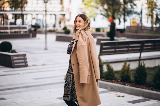 Bella donna in un cappotto beige fuori nel parco