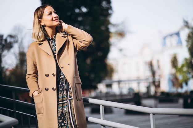 Bella donna in un cappotto beige fuori nel parco