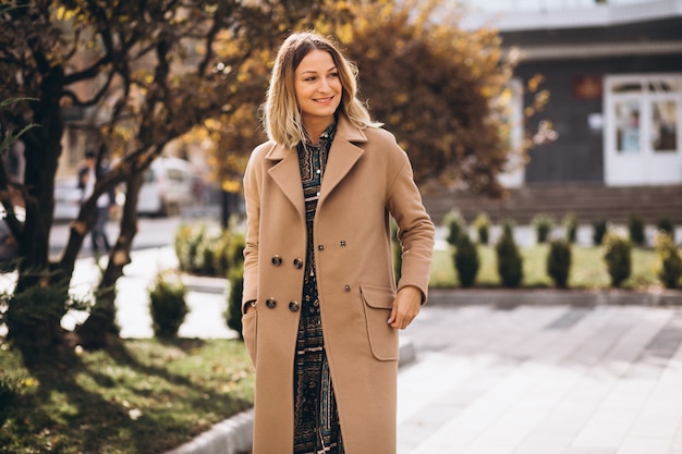 Beautiful woman in a beige coat outside in park