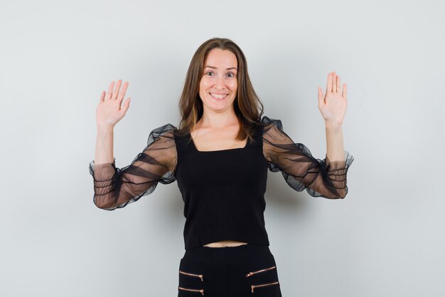 Free photo beautiful woman in black blouse raising hands up and looking merry