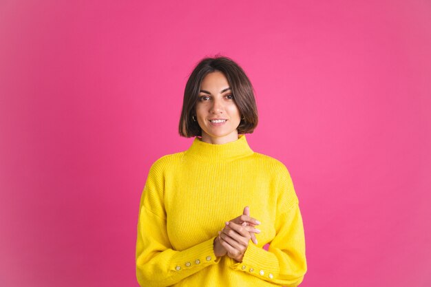 밝은 노란색 스웨터에 아름 다운 여자는 자신감이 미소로 앞으로 분홍색 모습에 고립