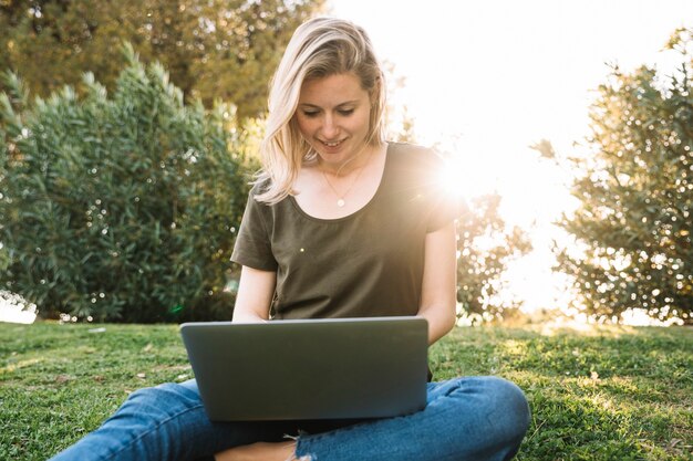 Beautiful woman browsing laptop on ground