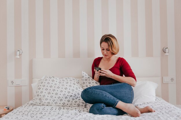 Beautiful woman browsing smartphone on bed