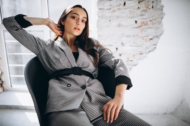 Beautiful woman in a business suit sitting in chair