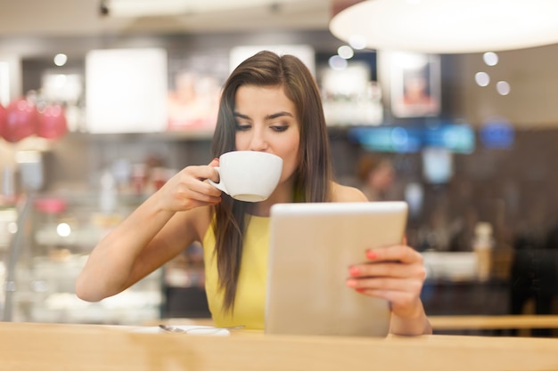 Красивая женщина в кафе с помощью цифрового планшета