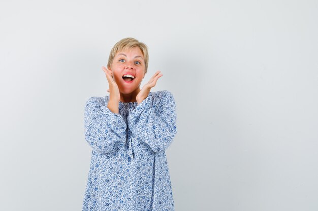 Beautiful woman calling someone with loud voice in patterned blouse and looking cheery. front view. space for text