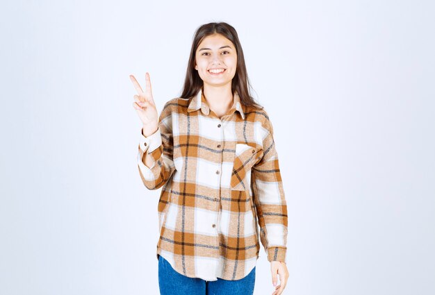 Beautiful woman in casual clothes standing on white wall. 