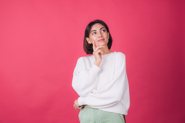 Free photo beautiful woman in casual white sweater on red wall