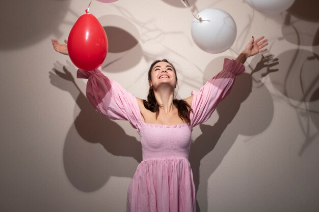 Beautiful woman celebrating valentines day in a pink dress with balloons