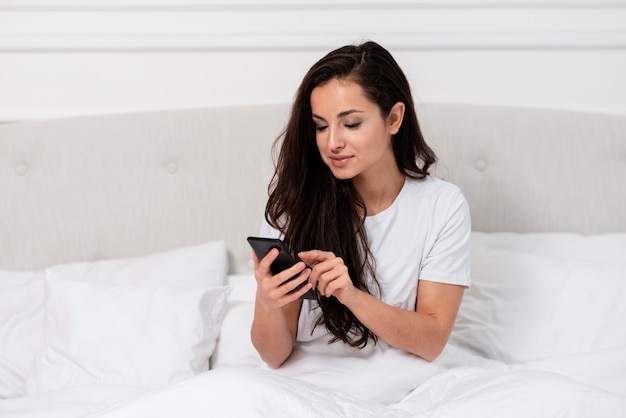 Beautiful woman checking her phone after waking up