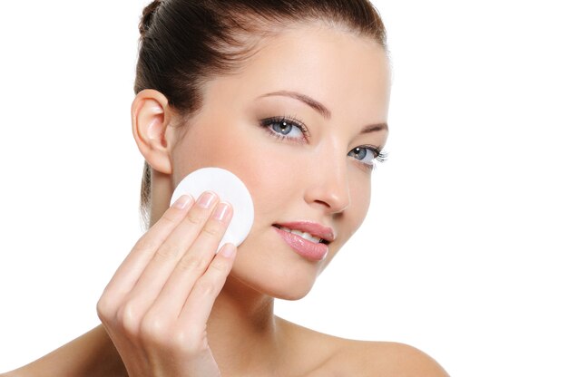 Beautiful woman cleaning her pretty face with cotton swab - over white background