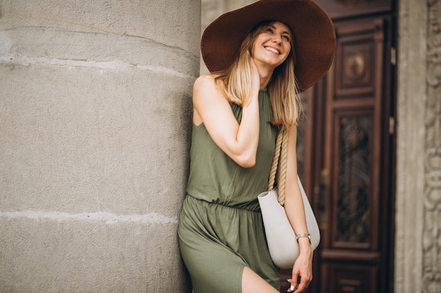 Beautiful woman in dress and hat standing by architecture