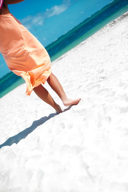 красивая женщина в платье, прогулки возле пляжа океана в летний день на белом песке