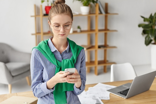 Foto gratuita bella donna vestita formalmente in ufficio con il telefono