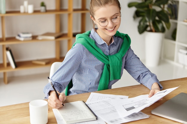 Beautiful woman dressed formally in office writing