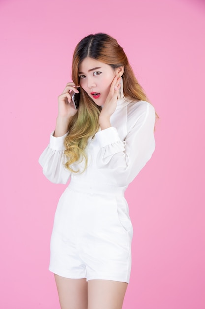 A beautiful woman dressed with a white dress, showing the phone and facial emotions
