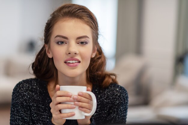 家で朝コーヒーを飲む美しい女性